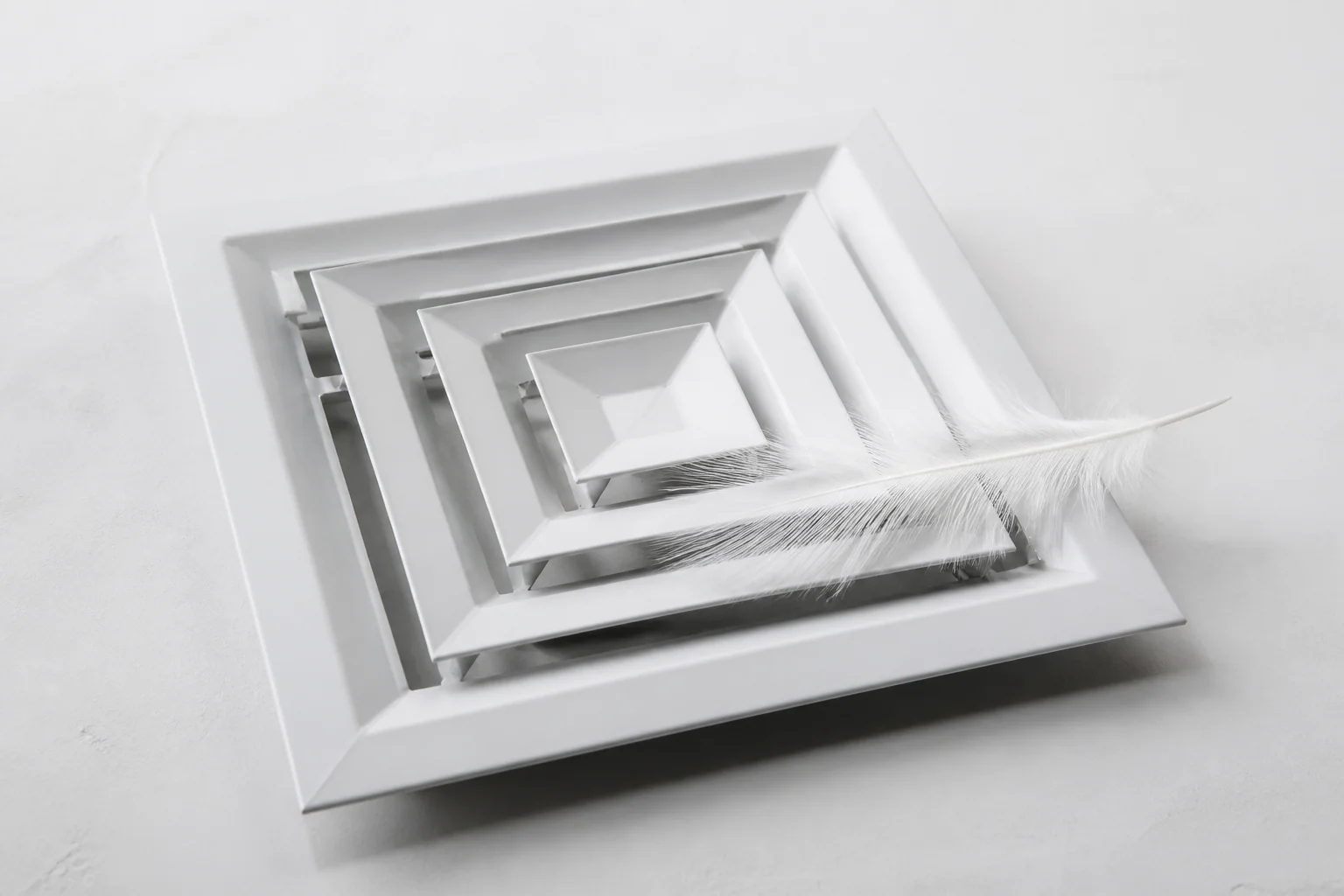 Bouche de ventilation et plume immobile — visuel conceptuel, l’air calme